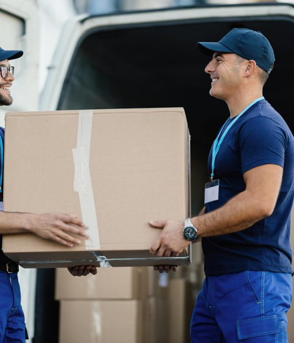 happy-manual-worker-cooperating-while-carrying-cardboard-boxes-delivery-van_637285-1258